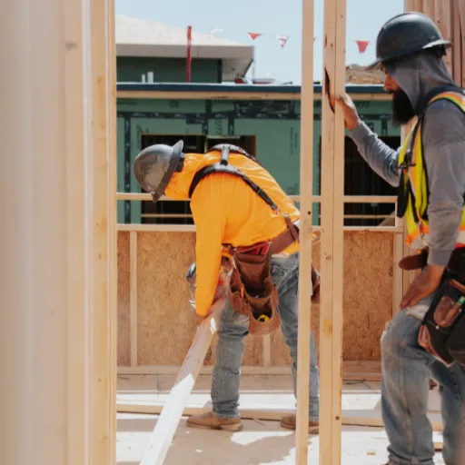 Two framing crew members positioning lumber inside a build