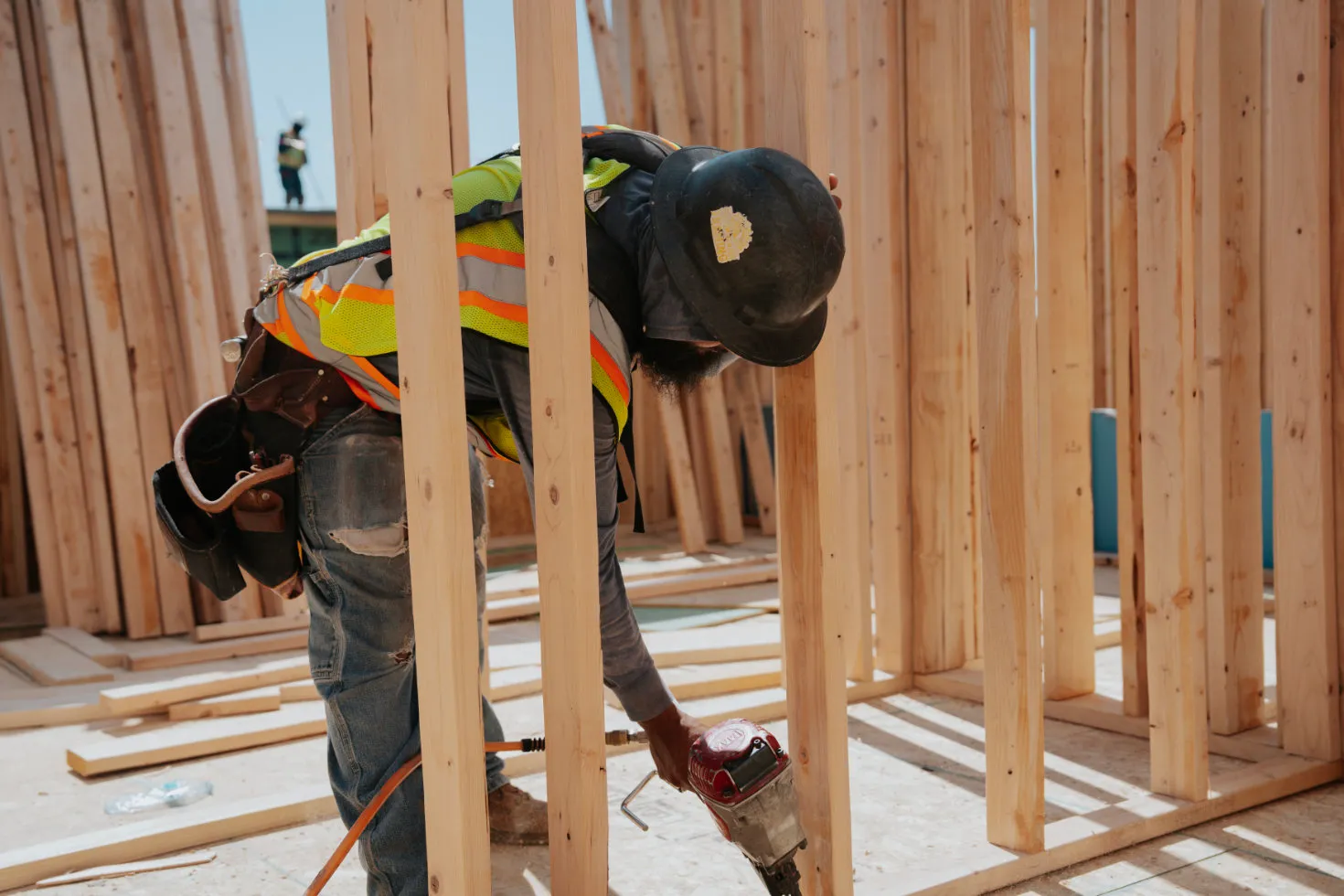 Crew member stepping onto a framed exterior deck with tools in hand