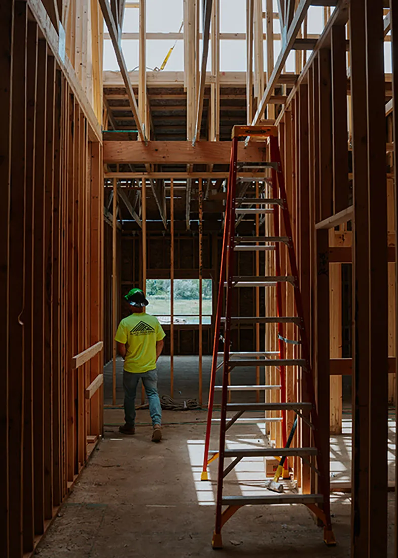 Interior framed hallway with a ladder and crew member in the distance